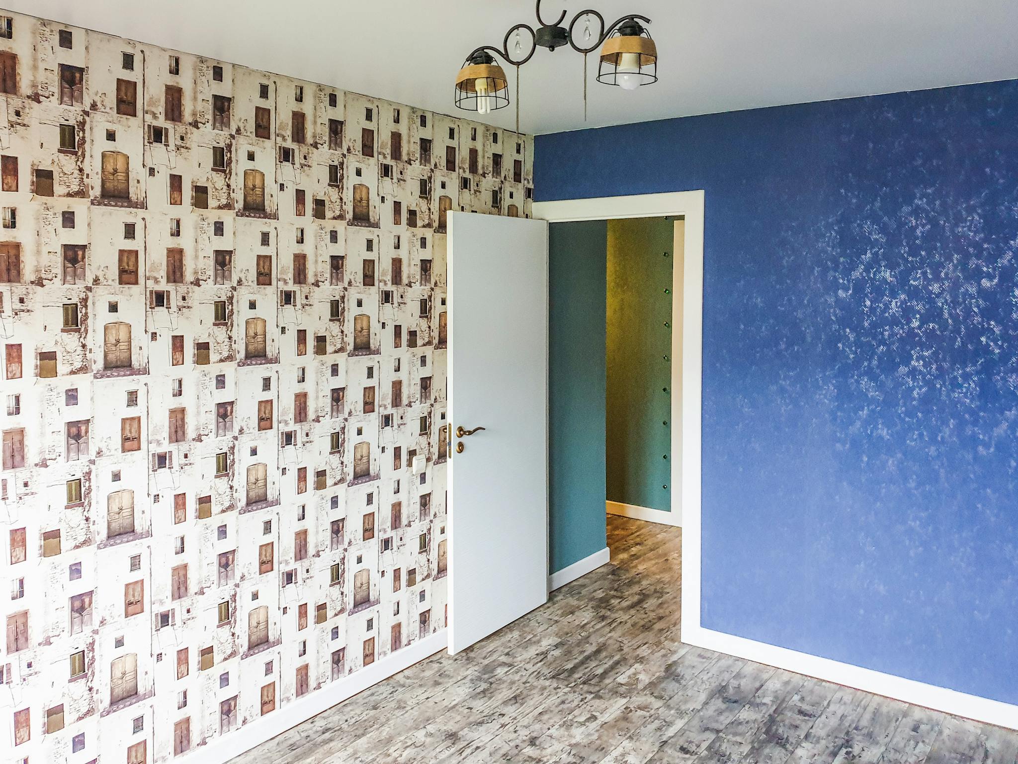 A modern room featuring a blue accent wall, unique patterned wallpaper, and contemporary lighting.