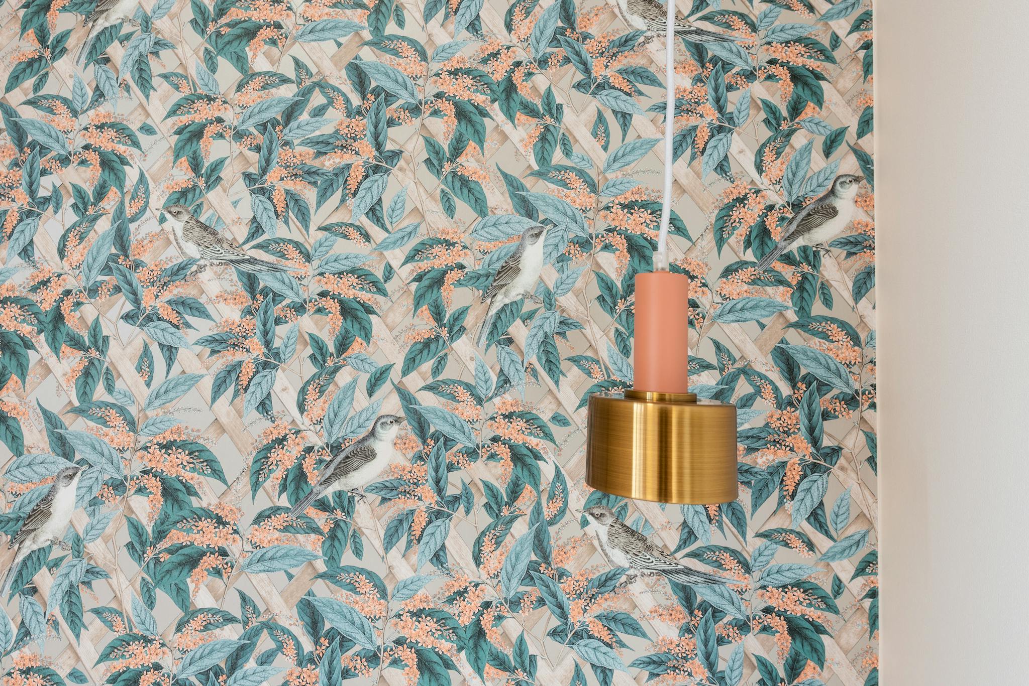 Metal lamp hanging near wall with colorful leaves in room in new flat